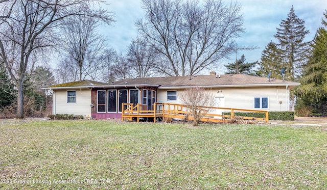 rear view of house featuring a lawn, a deck, and a sunroom