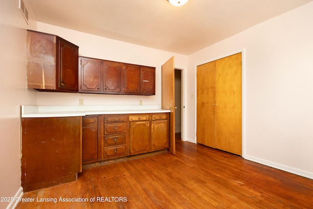 kitchen featuring visible vents, light countertops, baseboards, and wood finished floors