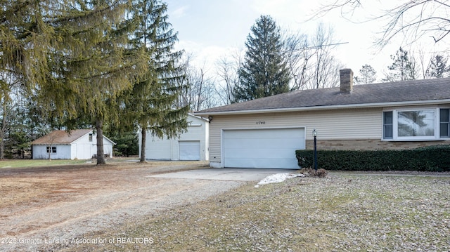 exterior space with driveway, a chimney, an attached garage, and a shingled roof