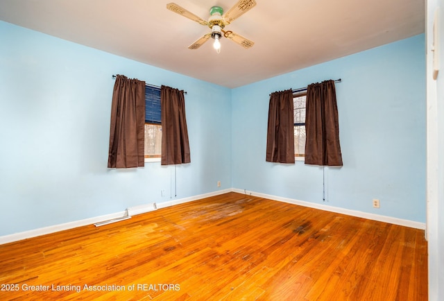 empty room featuring visible vents, ceiling fan, baseboards, and wood finished floors