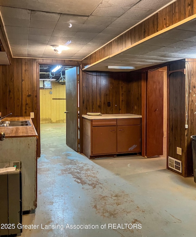 finished below grade area featuring a sink, visible vents, and wood walls