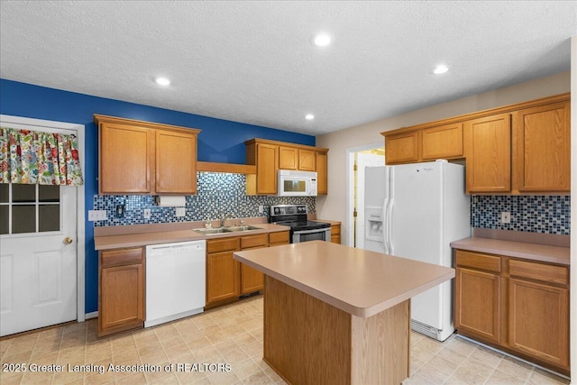 kitchen featuring white appliances, a kitchen island, light countertops, and a sink