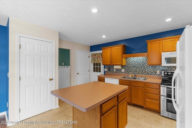 kitchen with white appliances, a kitchen island, a sink, light countertops, and tasteful backsplash