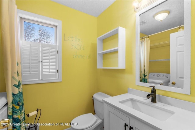 bathroom featuring washer / clothes dryer, a textured ceiling, toilet, and vanity