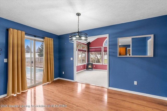 unfurnished dining area featuring wood finished floors, baseboards, and a textured ceiling