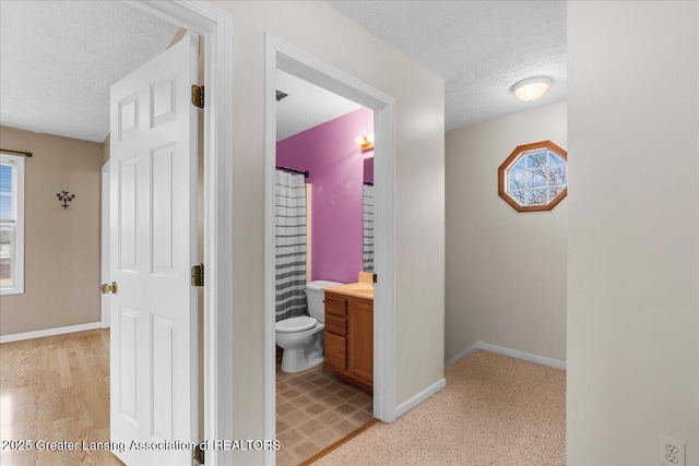 hallway with baseboards, a wealth of natural light, and a textured ceiling