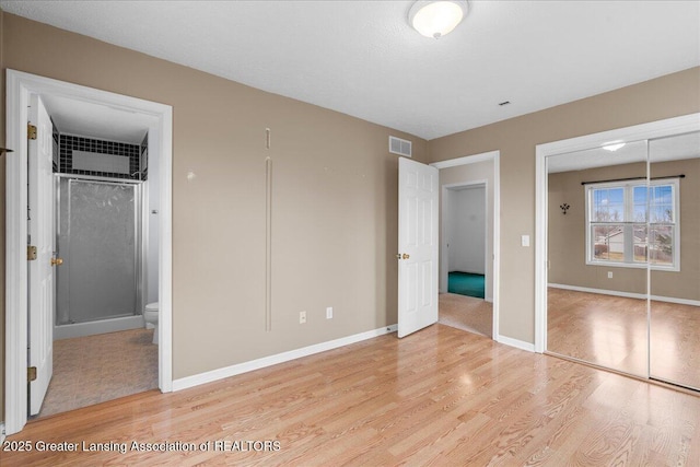 unfurnished bedroom featuring visible vents, baseboards, a closet, and light wood-style flooring