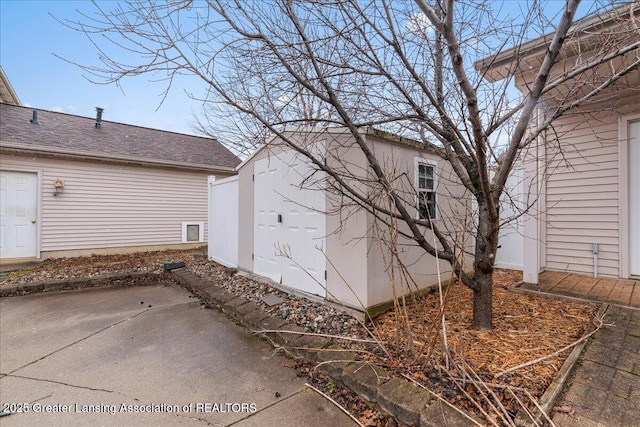 view of home's exterior featuring an outbuilding, roof with shingles, and a patio area