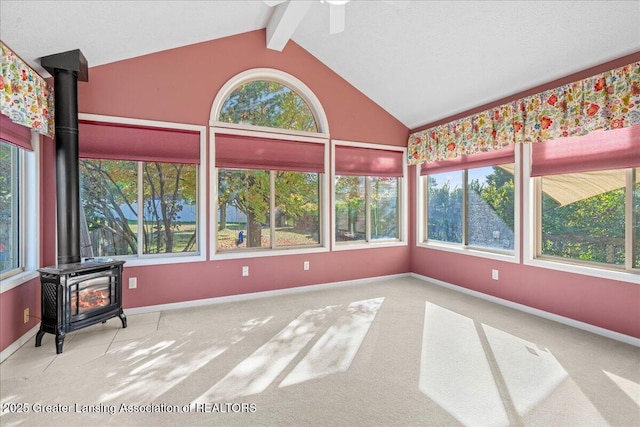 sunroom / solarium with a wealth of natural light, vaulted ceiling with beams, and a wood stove