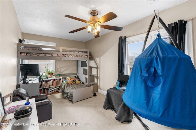 bedroom featuring multiple windows, a textured ceiling, carpet floors, and a ceiling fan