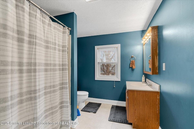 bathroom with vanity, toilet, baseboards, and a textured ceiling