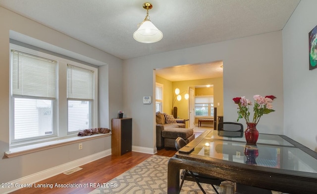 home office featuring visible vents, a healthy amount of sunlight, baseboards, and wood finished floors