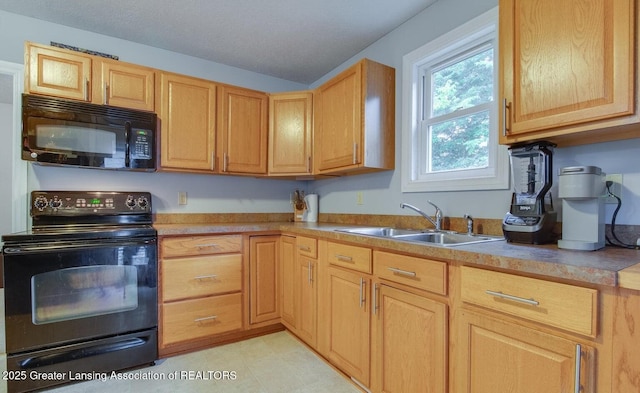 kitchen featuring a sink, black appliances, light brown cabinets, and light countertops