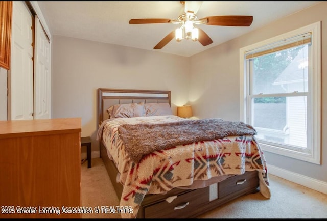 bedroom featuring a ceiling fan, light colored carpet, baseboards, and a closet