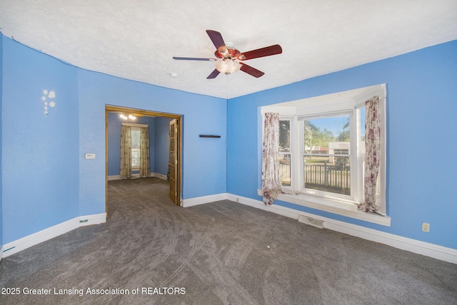 empty room featuring visible vents, carpet flooring, a ceiling fan, and baseboards