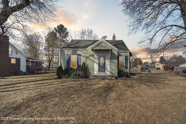 view of front of home featuring a chimney and a front lawn