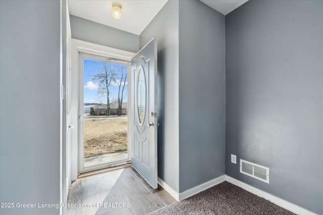 foyer entrance featuring a wealth of natural light, visible vents, baseboards, and wood finished floors