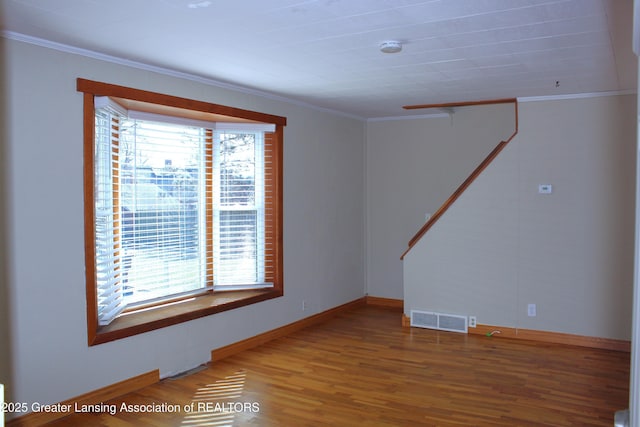 empty room featuring a wealth of natural light, visible vents, and crown molding