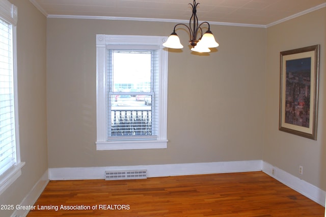 unfurnished room with a chandelier, visible vents, a wealth of natural light, and ornamental molding