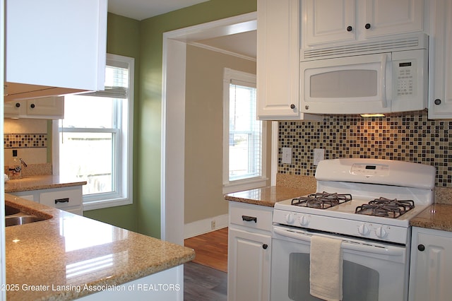 kitchen featuring white appliances, tasteful backsplash, wood finished floors, and white cabinetry