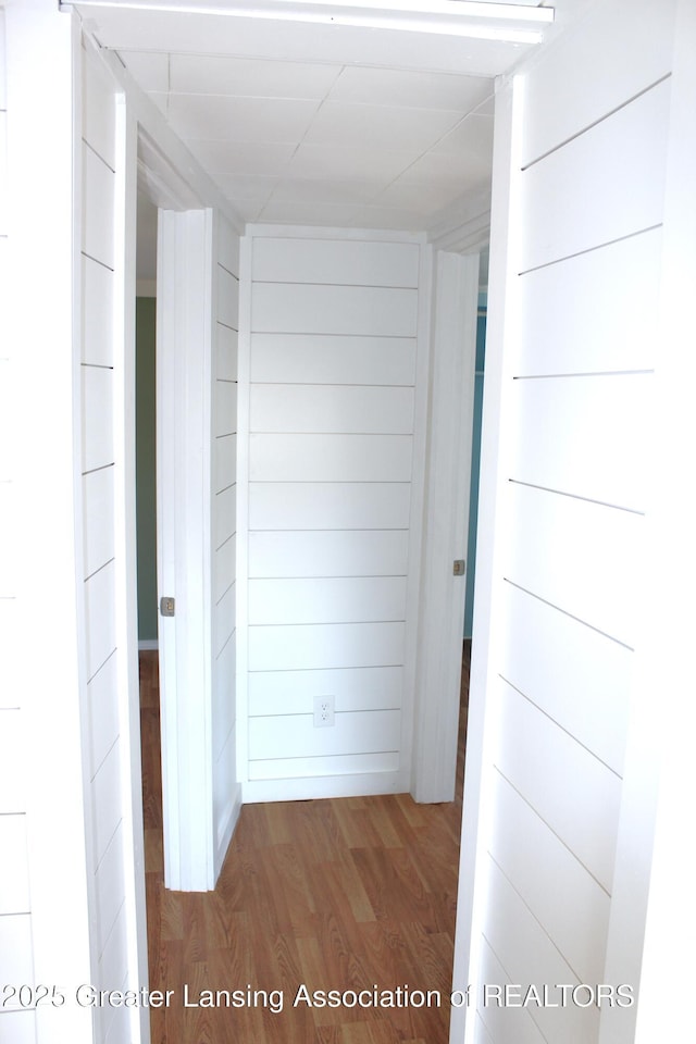 hallway featuring wooden walls and wood finished floors