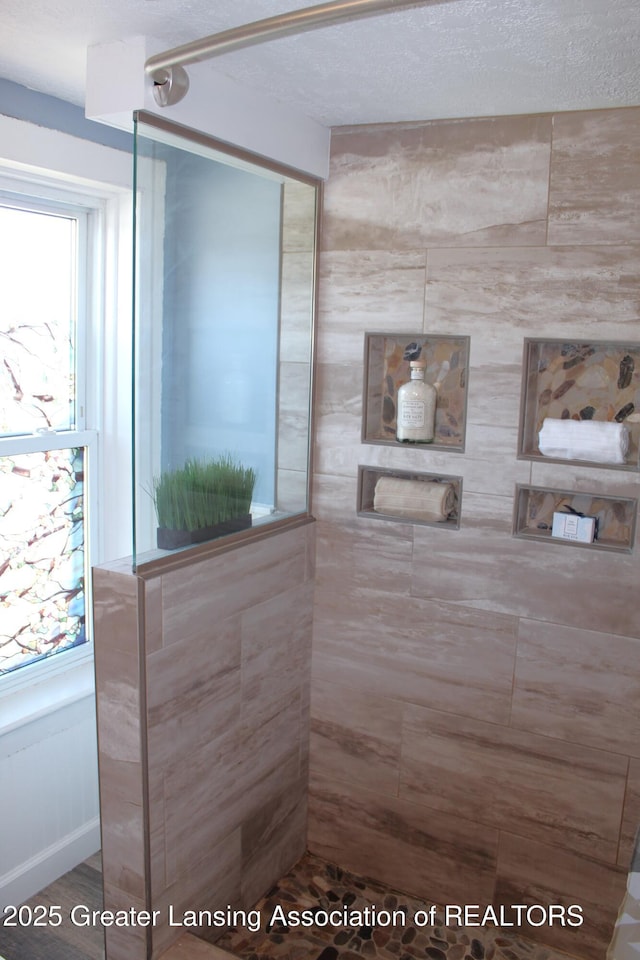 full bathroom with a textured ceiling and a tile shower