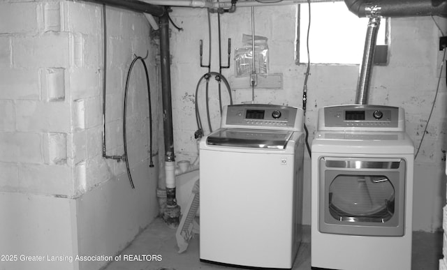 clothes washing area with laundry area, concrete block wall, and washing machine and dryer