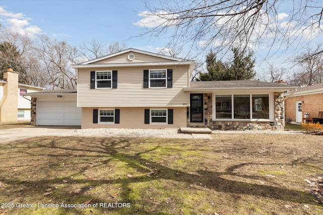 split level home featuring a front lawn, an attached garage, brick siding, and driveway