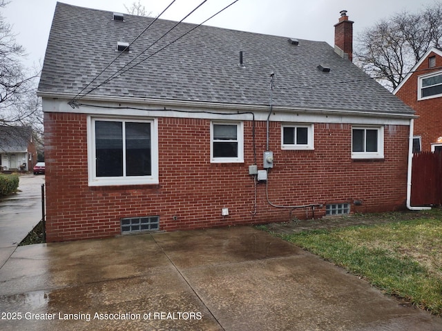 rear view of property featuring brick siding, a chimney, and a shingled roof