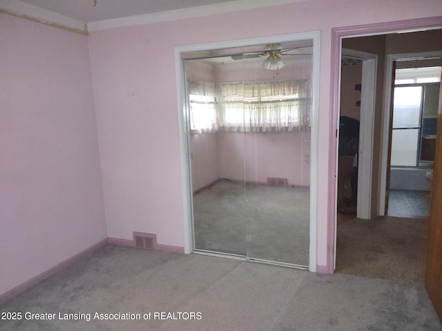 carpeted empty room featuring visible vents, baseboards, ceiling fan, and ornamental molding