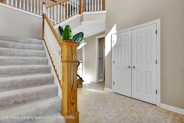 staircase with baseboards, a towering ceiling, and tile patterned flooring