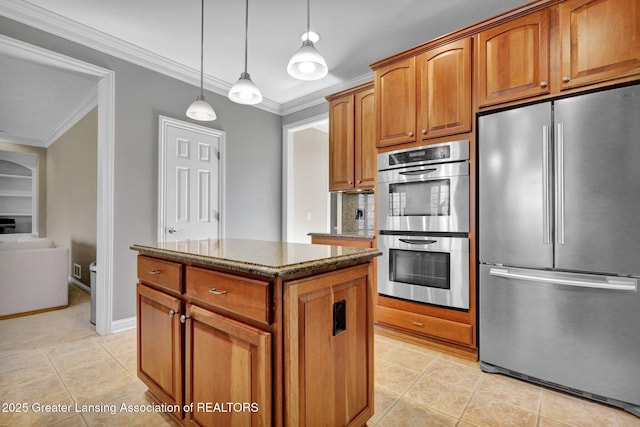 kitchen featuring dark stone counters, ornamental molding, appliances with stainless steel finishes, brown cabinets, and a center island