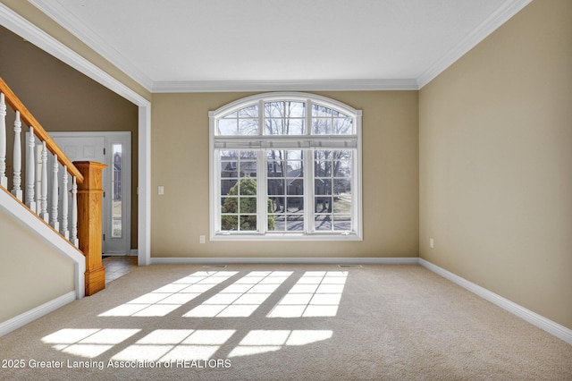 spare room featuring carpet flooring, crown molding, and baseboards