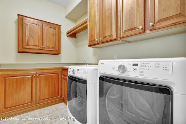 laundry area featuring light tile patterned floors, cabinet space, and washing machine and clothes dryer