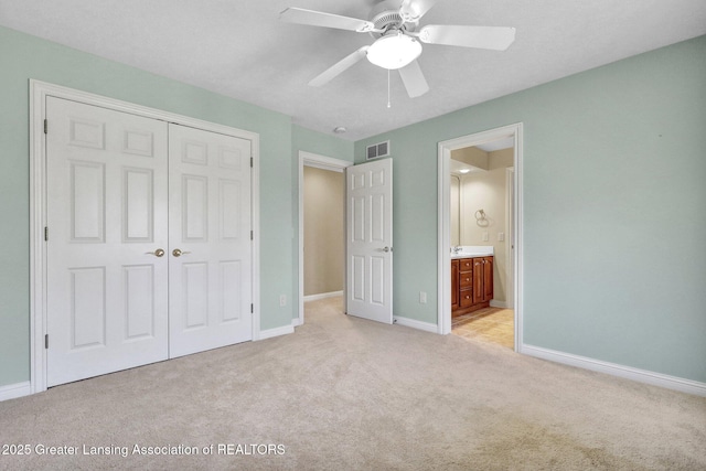 unfurnished bedroom with visible vents, connected bathroom, baseboards, light colored carpet, and a closet