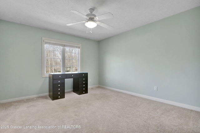 spare room featuring baseboards, carpet floors, visible vents, and ceiling fan