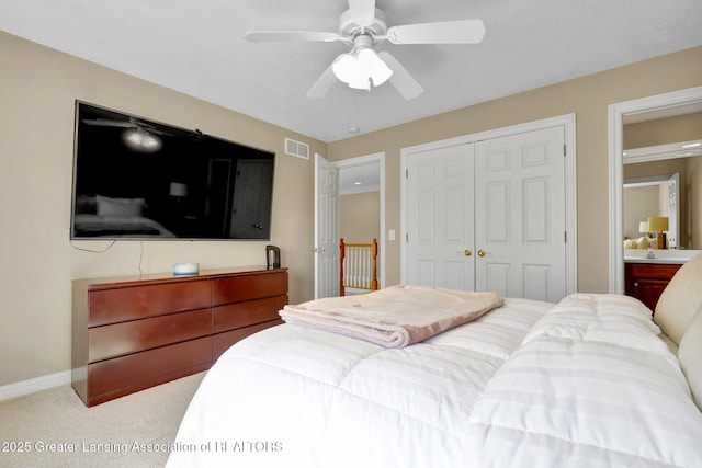 carpeted bedroom featuring a closet, visible vents, baseboards, and ceiling fan