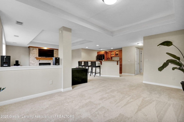 basement featuring light colored carpet, a large fireplace, baseboards, and black refrigerator