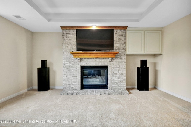 unfurnished living room featuring a tray ceiling, carpet, and a fireplace