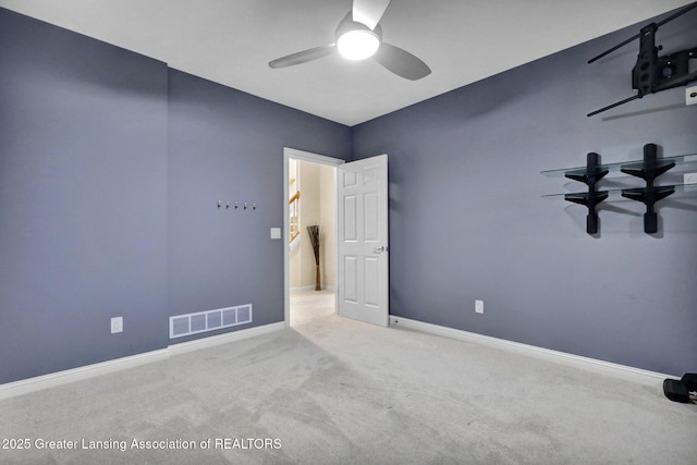 carpeted spare room with visible vents, baseboards, and a ceiling fan