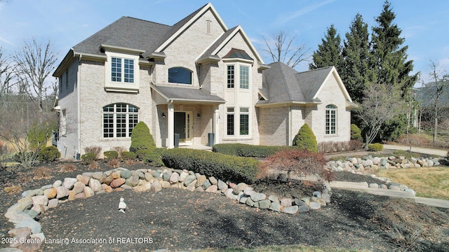 french country home featuring brick siding