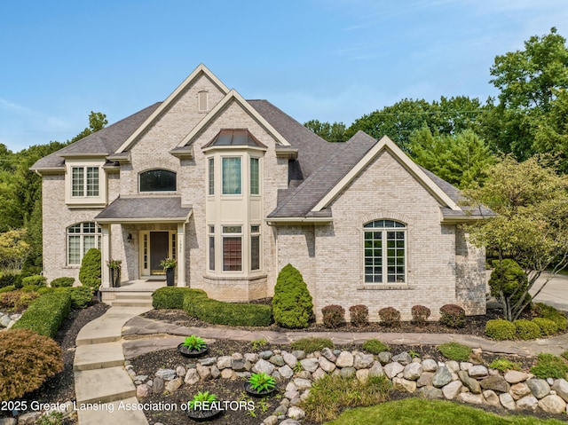 french country style house with brick siding and a shingled roof