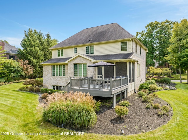 rear view of house featuring a lawn, a shingled roof, and a deck