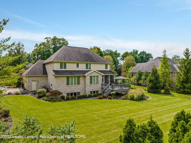 back of property with a lawn, a wooden deck, a garage, and a shingled roof