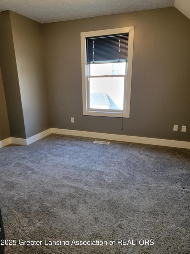 carpeted empty room with visible vents, baseboards, and a textured ceiling