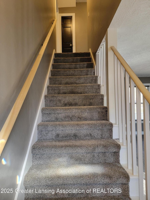 stairs featuring a textured ceiling