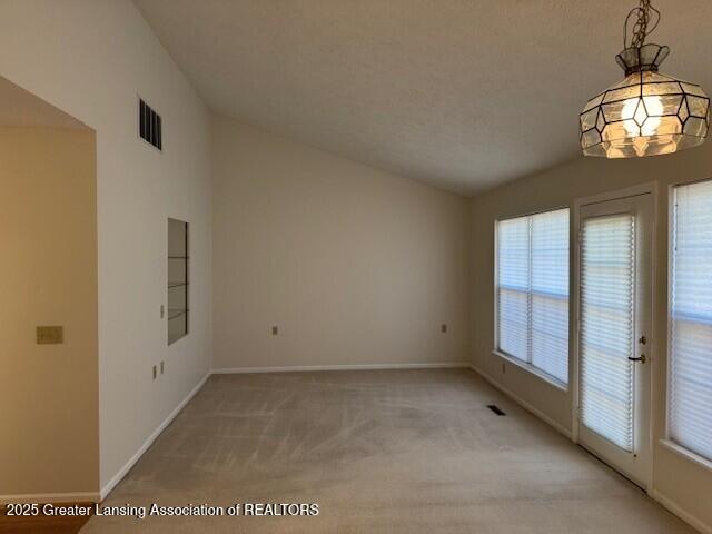 unfurnished room with visible vents, light colored carpet, baseboards, and lofted ceiling