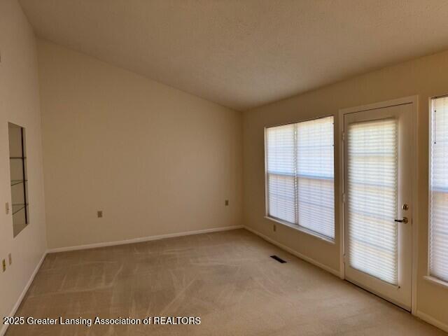 unfurnished room with visible vents, baseboards, and light colored carpet