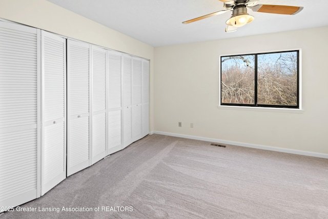 unfurnished bedroom with light carpet, visible vents, baseboards, and a closet