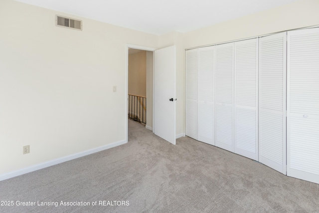 unfurnished bedroom with a closet, visible vents, carpet flooring, and baseboards